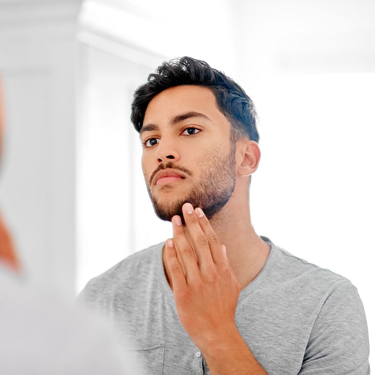 Man met baard kijkt in spiegel