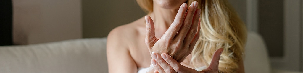 Oudere vrouw smeert haar handen in met handcrème.