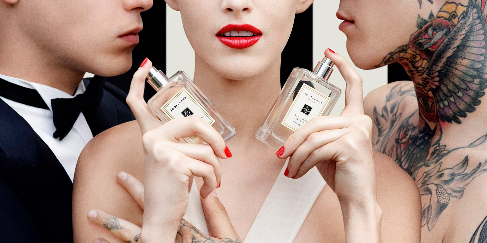 Woman sprays perfume on her neck with a black background.