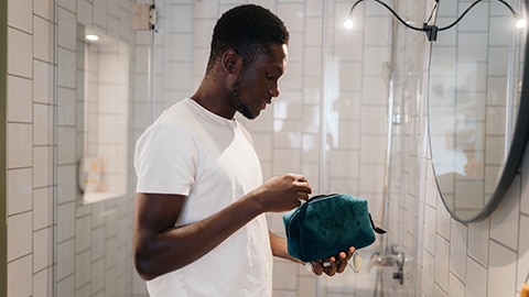 Man met toilettas in badkamer Man met toilettas in badkamer