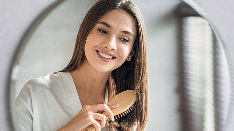 Vrouw met bruine haren doet haar haircare routine.						 Vrouw met bruine haren doet haar haircare routine.